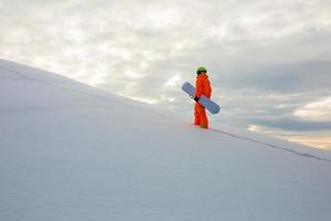 Snowboarder climbing on the top of ski slope photo