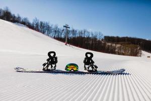 Bottom view on empty ski slope and equipment for snowboarding photo
