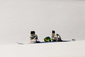 Snowboard and ski googles laying on a snow near the freeride slope photo