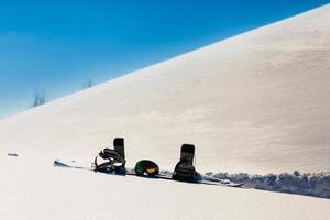 Snowboard and ski googles laying on a snow near the freeride slope photo