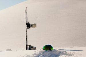 Snowboard and ski googles laying on a snow near the freeride slope photo