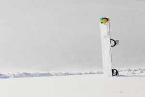 Gafas de snowboard y esquí tendido sobre la nieve cerca de la pista de freeride foto