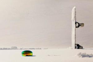 Snowboard and ski googles laying on a snow near the freeride slope photo