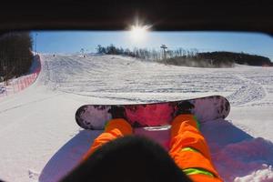 Punto de vista de un hombre snowboarder sentado en la nieve. foto