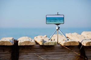 Smartphone on tripod making photo and video of sea landscape