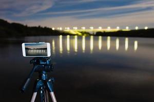 usando un teléfono inteligente como una cámara profesional en un trípode para capturar paisajes nocturnos foto