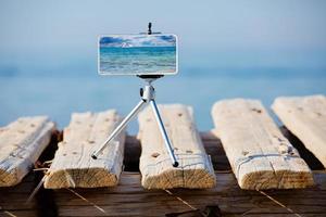 Smartphone on tripod making photo and video of sea landscape