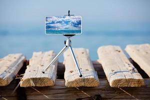 teléfono inteligente en trípode haciendo fotos y videos del paisaje marino