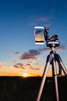 Smartphone on tripod capturing image of sundown in vertical mode photo