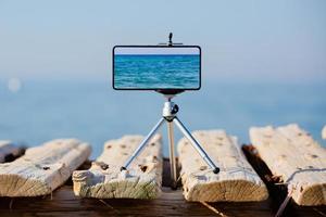 teléfono inteligente en trípode haciendo fotos y videos del paisaje marino