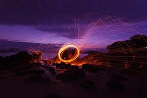 Swing fire Swirl steel wool light photography over the stone with reflex in the water Beautiful light in the sunrise or sunset time, long exposure speed motion style