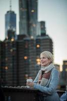 Mujer en el puente de Brooklyn mirando Manhattan con un café