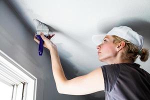 mujer pintando los bordes del techo