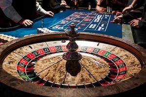 Detalles de la ruleta de madera brillante en un casino y personas foto