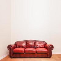 lujoso sofá de cuero rojo delante de una pared en blanco foto