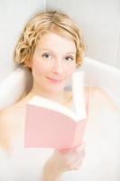 Young woman relaxing and reading a book in the bath photo