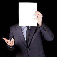 Businessman holding  an empty sheet of paper in front of his face photo