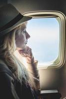 Mujer joven sola mirando afuera y sentado dentro del avión foto