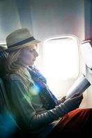 Young Caucasian Tourist Woman Alone Reading a Book Inside Airplane photo