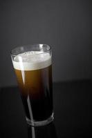 Proyecto de nitrógeno fresco y cremoso pinta de cerveza negra stout sobre fondo negro foto