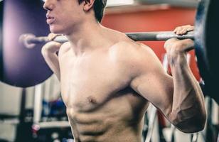 Crop man squatting with barbell photo