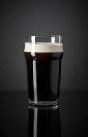 Proyecto de nitrógeno fresco y cremoso pinta de cerveza negra stout sobre fondo negro foto