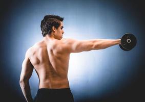 Sportsman with dumbbell in outstretched hand photo