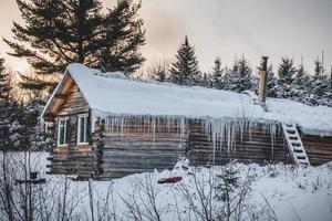 Cabaña de madera de troncos redondos canadienses durante el invierno foto