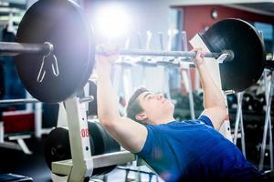 Man pressing barbell on incline bench. photo