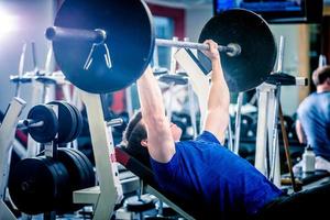 Man pressing barbell on incline bench. photo