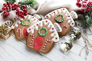 Homemade gingerbread houses  fir-tree branches and berries on white wooden table. photo