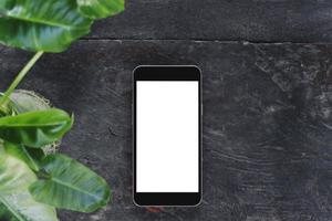 Black mobile phone blank screen white mockup with glass bottle green plant on top view and copy space. For using your concept photo