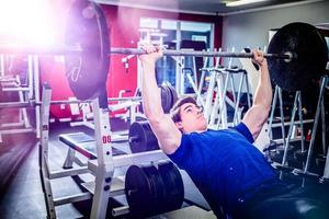 Man pressing barbell on incline bench. photo