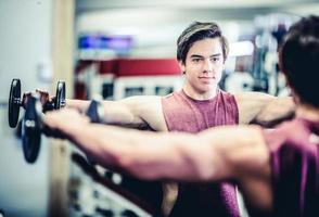 Hombre guapo musculoso con pesas en el gimnasio foto