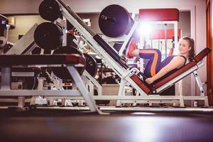 mujer deportiva, entrenamiento, piernas, en, máquina foto