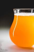 Close-up glass of homebrewed rhubarb beer with white foam. photo