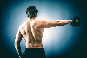 Sportsman with dumbbell in outstretched hand photo