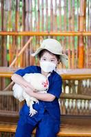 Portrait of a 5 year old girl visits an organic farm. Children try to touch the chicken. Concept of learning about farming animals. Vertical photos. photo