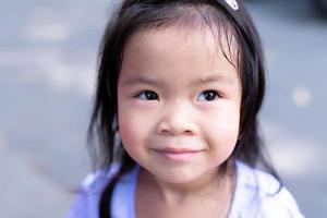 Close up of little girl's face was sweating due to the hot weather. Cute child sweet smiled. photo