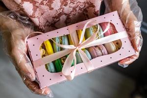 girl in protective gloves holds a package of homemade macarons for a gift photo