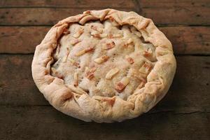 Whole salted pie with bacon on rough wooden table photo