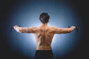 Hombre musculoso haciendo ejercicio de hombros con barra foto