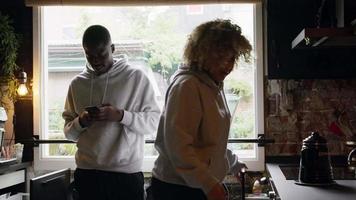 Mujer buscando algo y hombre mirando smartphone en la cocina video
