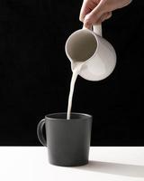 front view hand pouring milk into mug