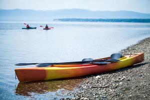 Kayak on the Sea Shore with Kayakers in the Background photo