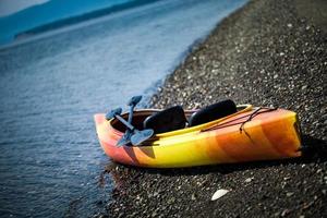 kayak naranja y amarillo con remos en la orilla del mar foto