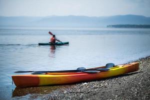 Kayak on the Sea Shore with Kayakers in the Background photo