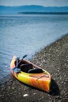 kayak naranja y amarillo con remos en la orilla del mar foto