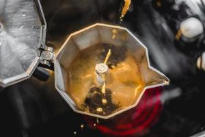 Cafetera italiana de aluminio preparando un café oscuro recién hecho en la estufa