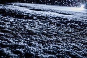 Textura de nieve retroiluminada durante la tormenta de nieve por la noche foto